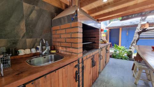 uma cozinha com um lavatório e um forno de tijolo em Blue House Cabaña - Departamento - Habitación em Pucón