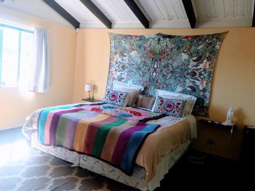 um quarto com uma cama com um cobertor colorido em Casa Ísis- Chapada dos Veadeiros em Alto Paraíso de Goiás