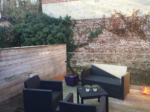 a patio with chairs and tables and a brick wall at Chambre chez Françoise in Spa