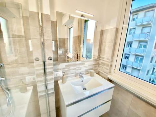 een badkamer met een wastafel, een douche en een raam bij Duomo a 15 minuti - Lussuoso appartamento in Milaan