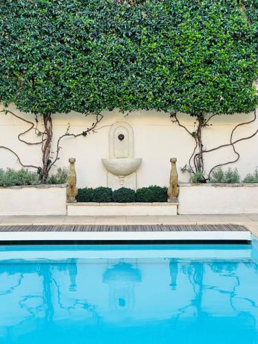 une piscine devant un mur avec une fontaine dans l'établissement Beautiful and spacious 3 bed character home with large, private heated pool, à Pouzolles