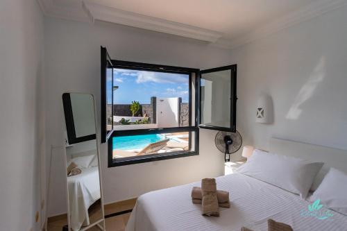 Un dormitorio con una cama y una ventana con piscina. en Villa Sara, en Playa Blanca