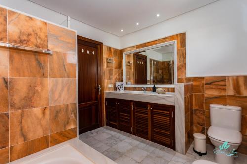 Un baño con lavabo, inodoro y espejo. en Villa Sara, en Playa Blanca