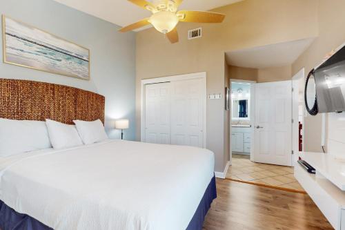 a bedroom with a large white bed and a flat screen tv at Baywatch F9 in Pensacola Beach