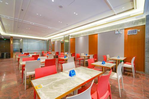 a restaurant with wooden tables and red chairs at Guangdong Baiyun City Hotel in Guangzhou