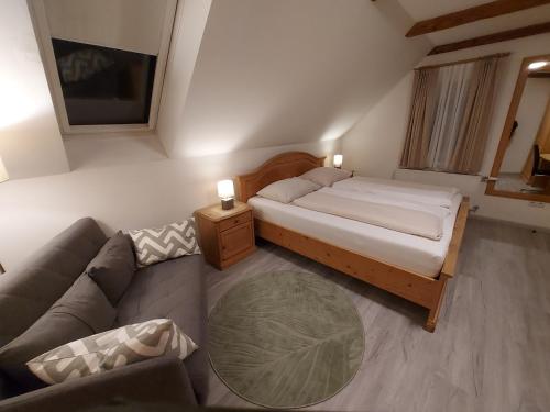 ein kleines Schlafzimmer mit einem Bett und einem Sofa in der Unterkunft Wollsdorferhof in Sankt Ruprecht an der Raab
