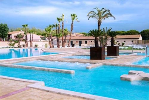 une piscine avec de l'eau bleue et des palmiers dans l'établissement Belle villa de vacances, residence TAMARIS, wifi, 2 chambres climatisées, 4 à 6 couchages - PORTIRAGNES PLAGE LRTAMA45, à Portiragnes