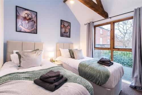two beds in a room with a window at Stunning Old Forge with Huge Balcony in Leamington Spa