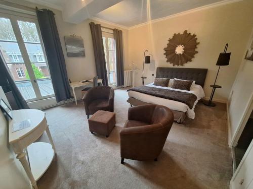 a bedroom with a bed and two chairs and a bed and a mirror at Domaine de Joinville in Eu