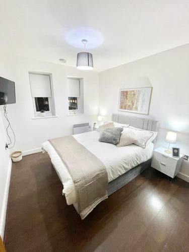 a white bedroom with a large bed and two windows at Modern Apartment in Stratford in London