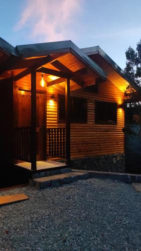 a wooden cabin with a porch and lights on it at Cabinas El Quetzal in San Gerardo de Dota