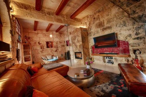 un soggiorno con divano in pelle e parete in pietra di Luxury House of Character Golden Bay/Manikata. a Ix-Xagħra l-Ħamra