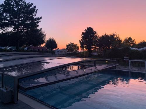 a bridge over a swimming pool at sunset at Lug ins Land Restaurant & Ferienwohnungen in Bad Bellingen