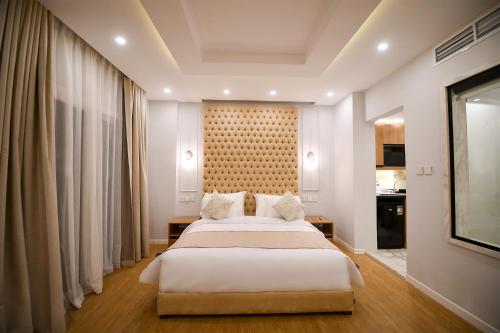 Un dormitorio con una gran cama blanca y una pared en Arabella Premium Residence - New Cairo, en El Cairo