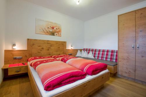 a large bed with red and orange blankets on it at Margarete Gwehenberger in Kleinarl