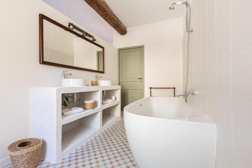 a white bathroom with a tub and a mirror at La Maison des Vendangeurs in Argelès-sur-Mer