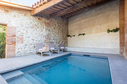- une piscine avec 2 chaises et un mur en briques dans l'établissement La Maison des Vendangeurs, à Argelès-sur-Mer