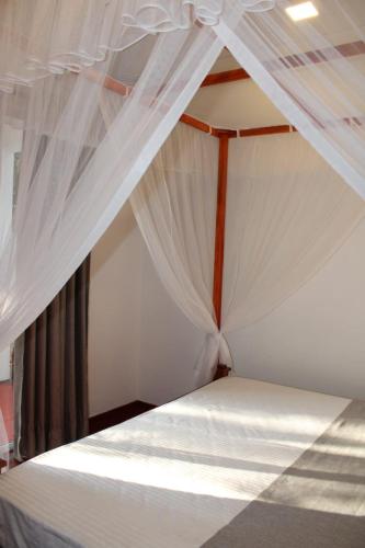 ミリッサにあるTHE LODGEのベッドルーム(白いカーテン付きの天蓋付きベッド1台付)