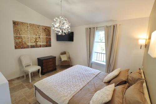 een slaapkamer met een bed en een kroonluchter bij Chambres d'hôtes avec Jacuzzi et Piscine au Mas de Cadoule in Saint-Just