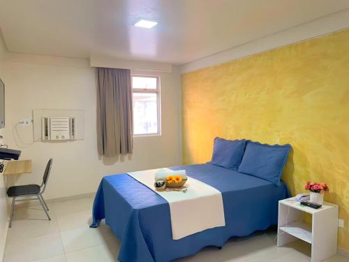 a bedroom with a blue bed with a bowl of fruit on it at Hotel Boa Viagem Aeroporto in Recife
