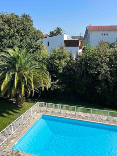 une piscine bleue avec une clôture blanche et des arbres dans l'établissement Design One bedroom with balcony, à Bidart
