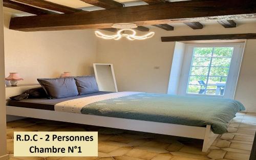um quarto com uma cama com um lustre e uma janela em Les Longères de Belle Vue - à 30' du Parc de Loisir du PAL em Bourbon-Lancy