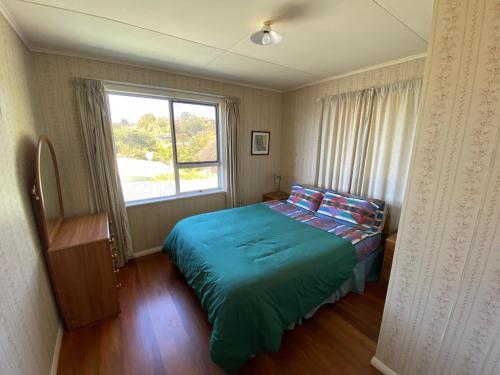 a small bedroom with a bed and a window at By the Seashaw - Hosted by Lorna, Michael & Katja in Parapara 