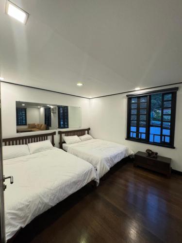 1 dormitorio con 2 camas y ventana en Colione Bed and Breakfast en Baguio