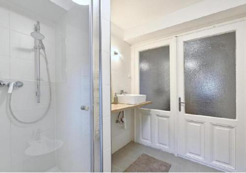 ein weißes Bad mit einer Dusche und einem Waschbecken in der Unterkunft Luxurious, 2 min to Casino and Römertherme in Baden