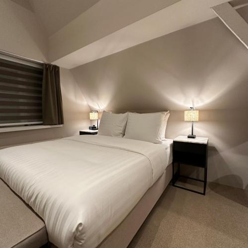 a bedroom with a large white bed with two lamps at Hotel Grand Canal in Delft