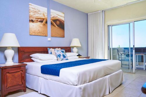 ein Schlafzimmer mit einem großen Bett und einem Balkon in der Unterkunft Tropical Sunset Beach Apartment Hotel in Saint James