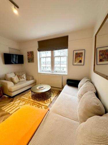 a living room with a couch and a table at Bright and Airy Two Bedroom Apartment in London