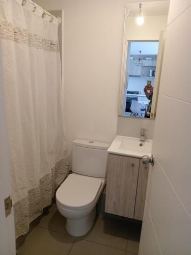 uma casa de banho com um WC, um lavatório e um espelho. em Departamento Amoblado y equipado Concepcion em Concepción