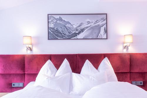 a bedroom with a bed with a red headboard and mountains at Hotel Sonnenheim in Sankt Anton am Arlberg