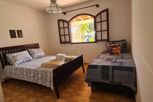 um quarto com uma cama e uma janela em Recanto da Praia Linda em São Pedro da Aldeia