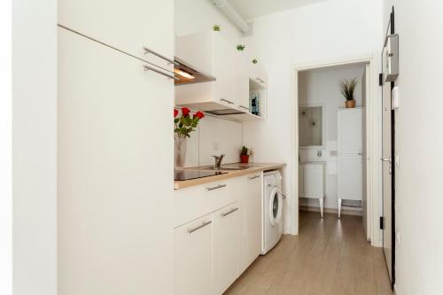 a kitchen with white cabinets and a washer and dryer at The Tropical Place in Milan