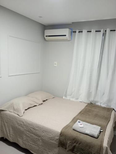 a bed in a room with a window and avertisement at apartamento confortavel no aracagir ,1 km da praia. in São Luís