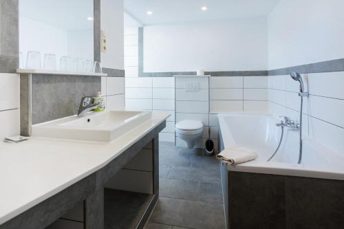 a bathroom with a sink and a tub and a toilet at Pension & Ferienwohnungen Töpferstüb'l in Saalfeld