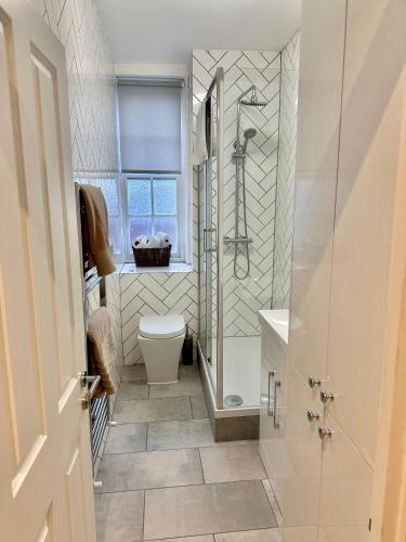 a bathroom with a shower and a toilet and a sink at Bright and Airy Two Bedroom Apartment in London