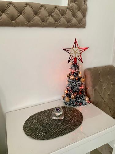 a christmas tree on a white table with a couch at Guesthouse Vladimir & Ana in Pančevo