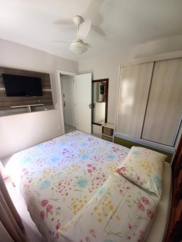 1 dormitorio con 1 cama grande con colcha de flores en Apto 1 quarto em BC, vista mar, ar condicionado split no quarto e na sala, en Balneário Camboriú