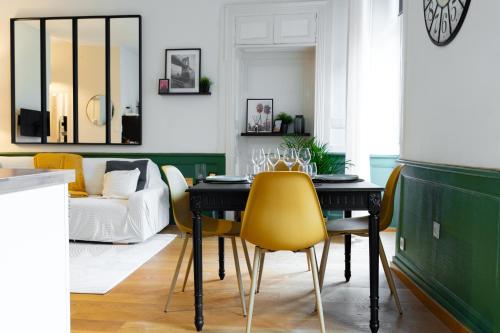 a dining room with a black table and yellow chairs at Chez Louise et Paul, l'Appart du Centre in Dinan