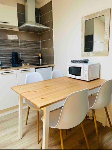 a kitchen with a wooden table with chairs and a microwave at Le Grand Studio in Castres