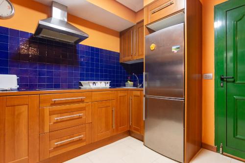 a kitchen with wooden cabinets and a stainless steel refrigerator at Tuscan Sea View in Costa Teguise