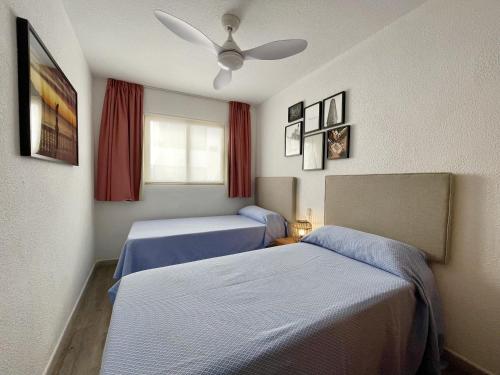 a bedroom with two beds and a ceiling fan at Pescadors Aprtment in Benidorm