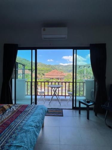 a bedroom with a bed and a balcony with a view at Petunya Phuket Guest House in Ban Huai Luk (1)