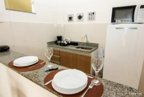 a kitchen with two white plates and two wine glasses at Apart Sol Nascente in Itatiaia