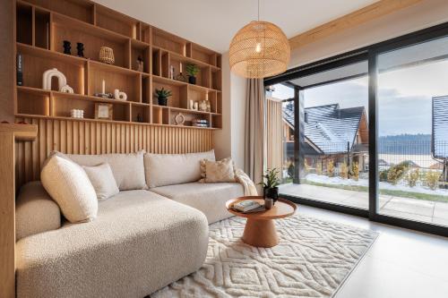 a living room with a couch and a large window at Stylchyn Park - Czorsztyn Exclusive - by Upstairs in Kluszkowce