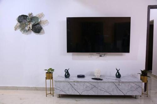 a living room with a tv on a white wall at Veetil -3BHK A/C, Kukatpally, Hyderabad in Hyderabad