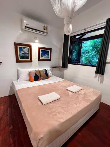 a bedroom with a large bed with two towels on it at Ko Phangan Haad Yao Beach Hotel in Haad Tian